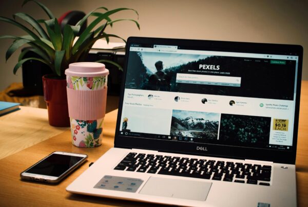 laptop on desk with screen open to a website. Coffee and cell phone on desk next to laptop.